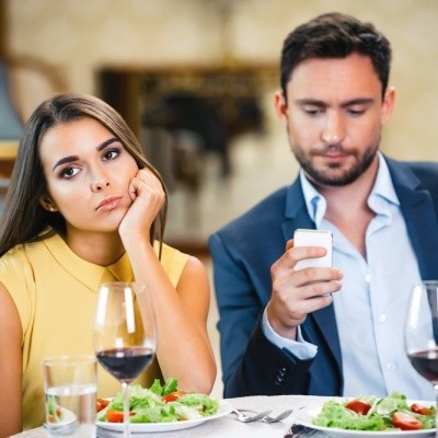 Woman upset about man looking at his phone in restaurant