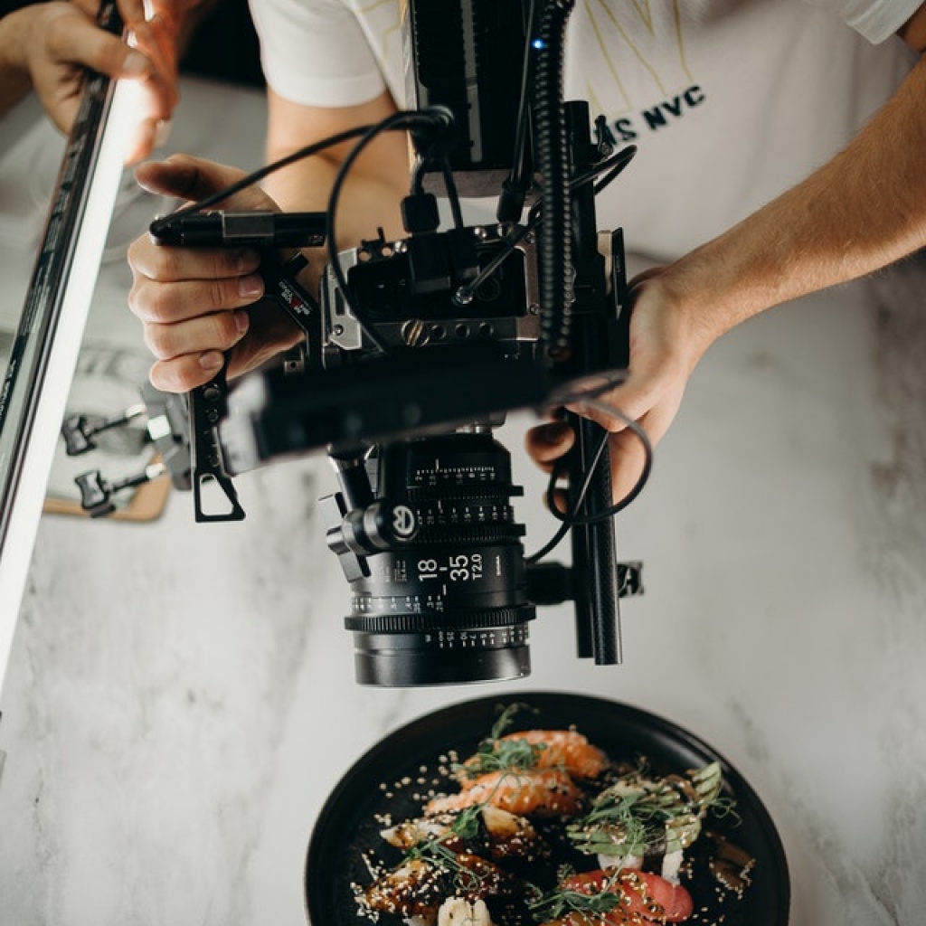 Man using camera to film delicious salmon food dish