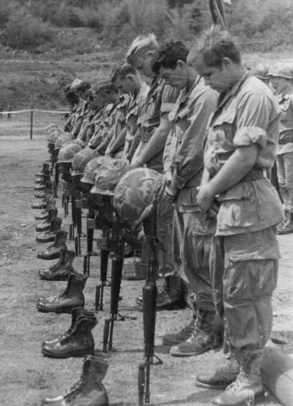 Soldiers standing with weapons and heads bowed down
