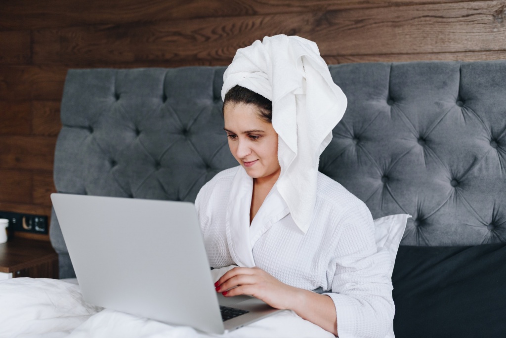 A woman with a towel on her head while operating a computer