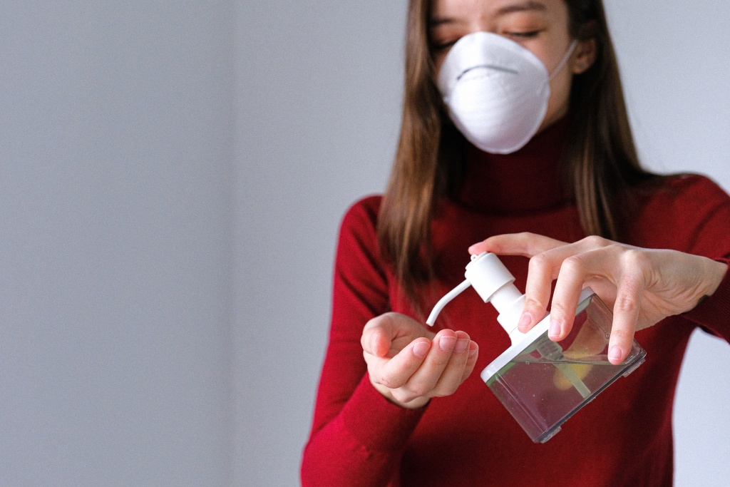 A girl with face mask using hand sanitizer