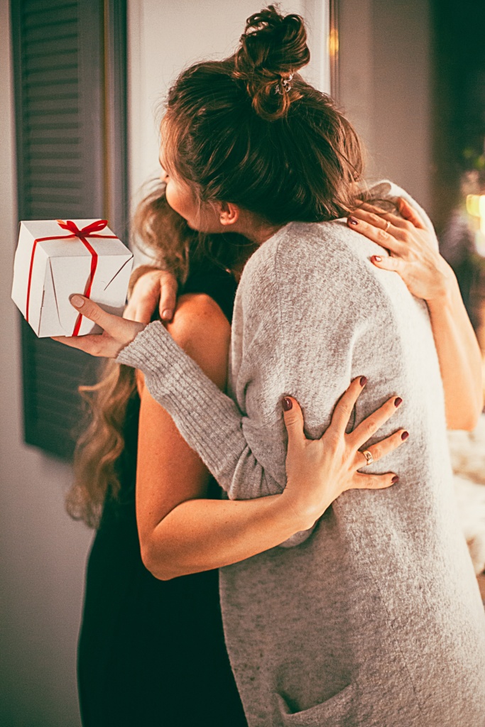 A lady hugging her friend with gift in her hand
