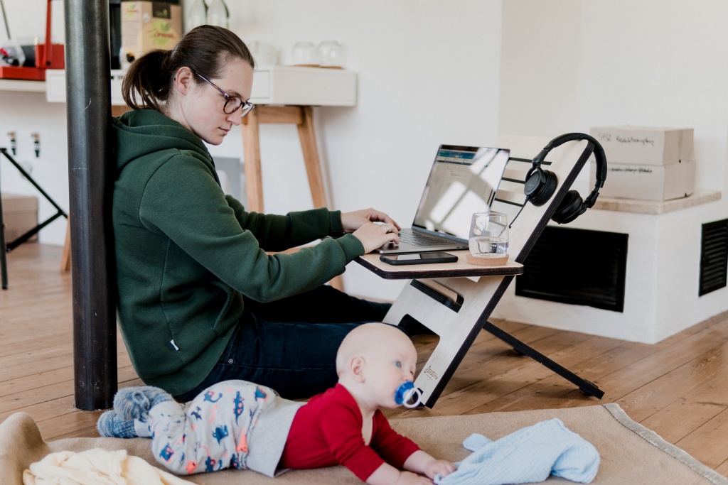 A mother operating a computer and caring for her baby