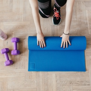 lady rolling up blue exercise mat